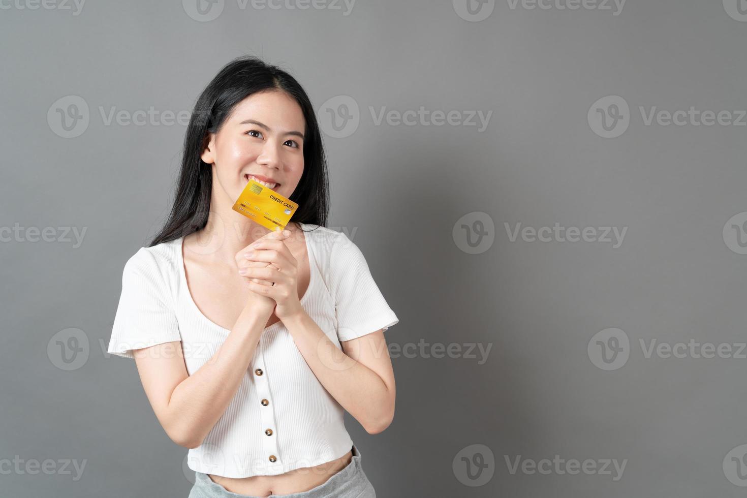 Asian woman with happy face and presenting credit card in hand showing trust and confidence for making payment photo