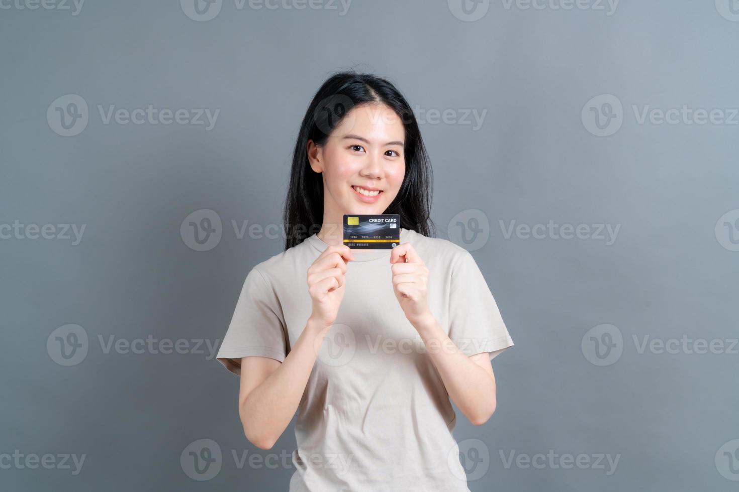 Portrait of a lovely young Asian woman showing credit card photo