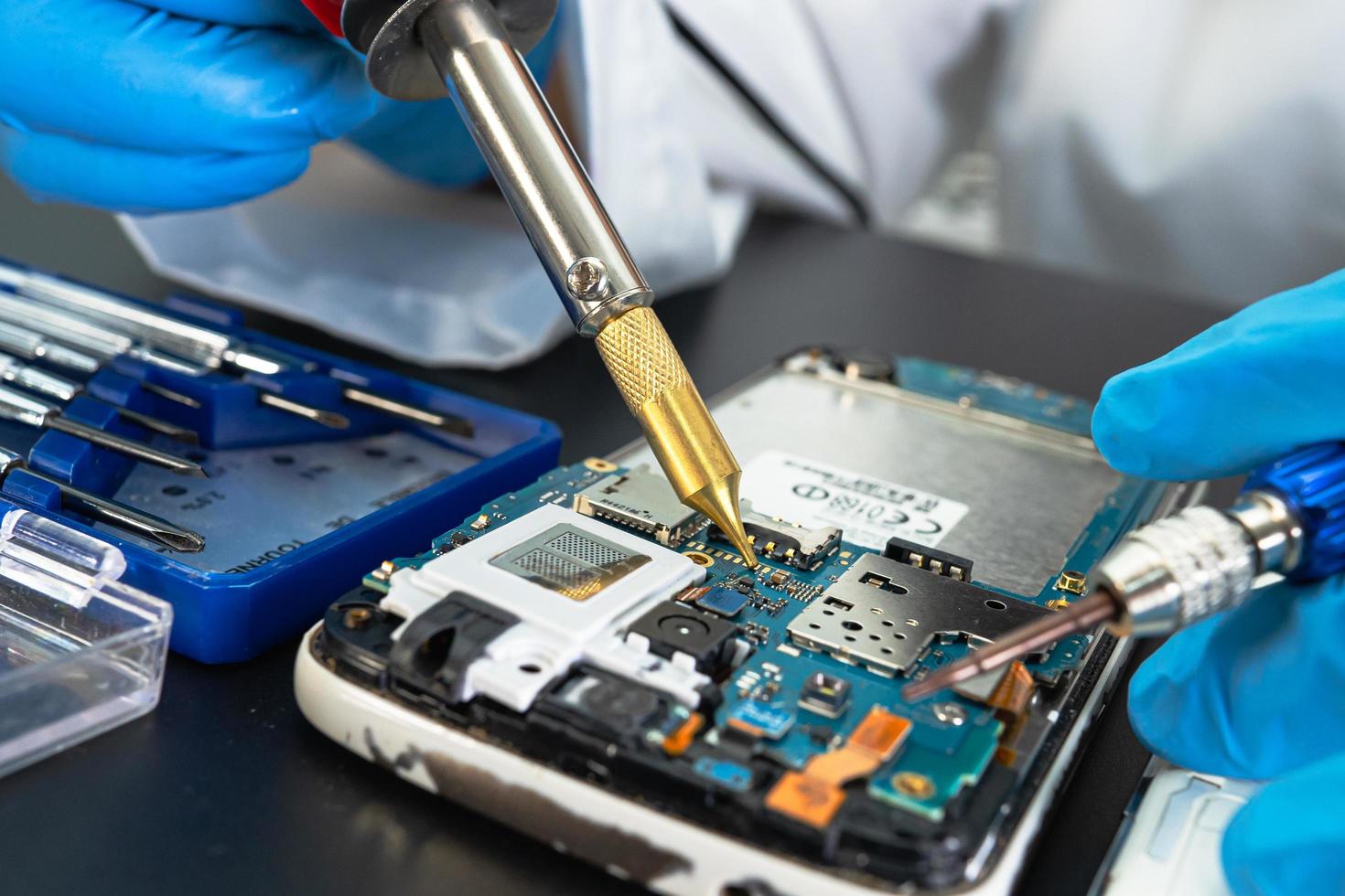 Technician repairing inside of mobile phone by soldering iron. Integrated Circuit. the concept of data, hardware, technology. photo