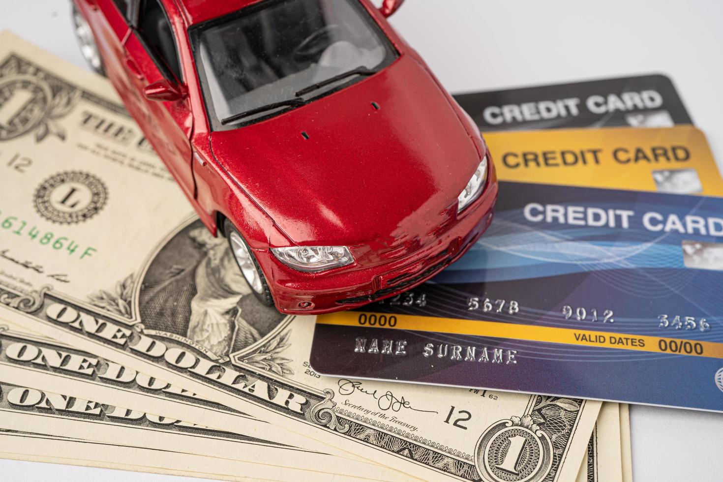 coche rojo con tarjeta de crédito y billetes de dólar estadounidense, concepto de préstamo de coche, seguro y tiempo de arrendamiento. foto