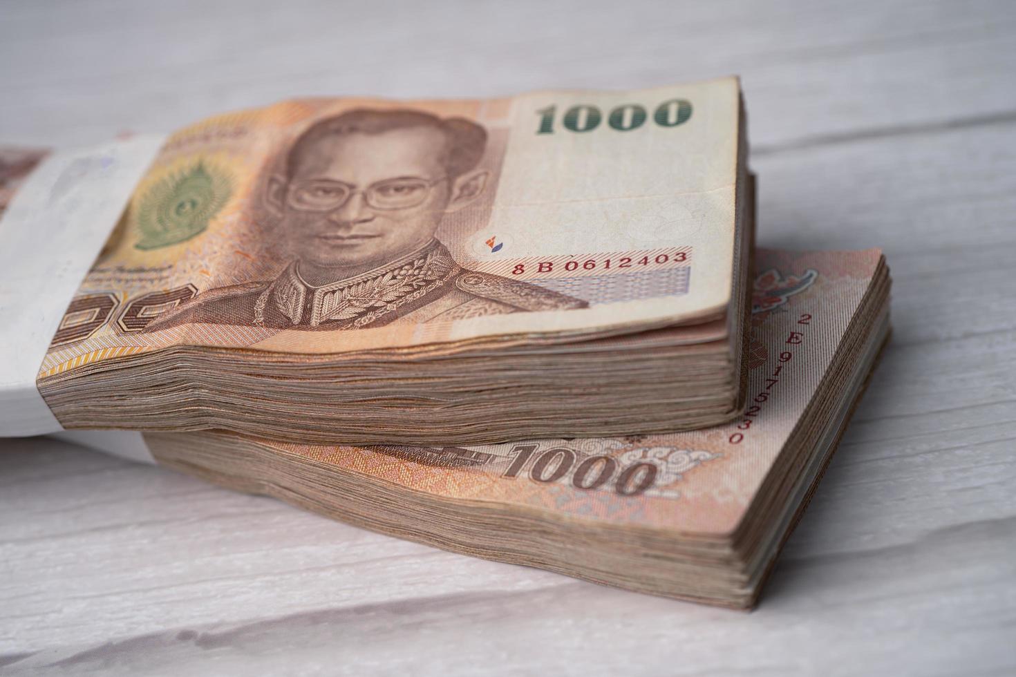 Stack of Thai baht banknotes on wooden background, business saving finance investment concept. photo