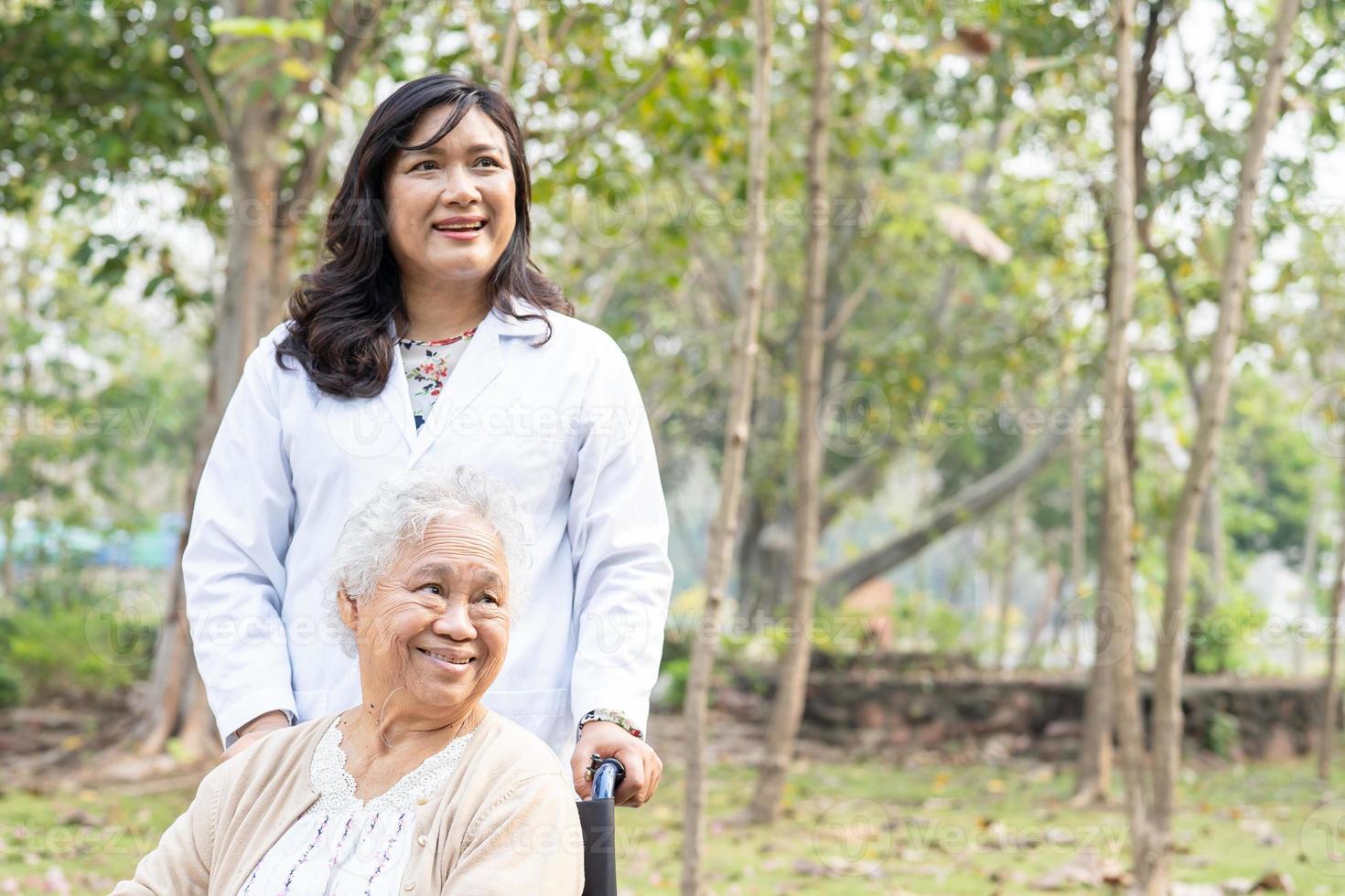 Asian senior or elderly old lady woman patient with care, help and support on wheelchair in park in holiday, healthy strong medical concept. photo