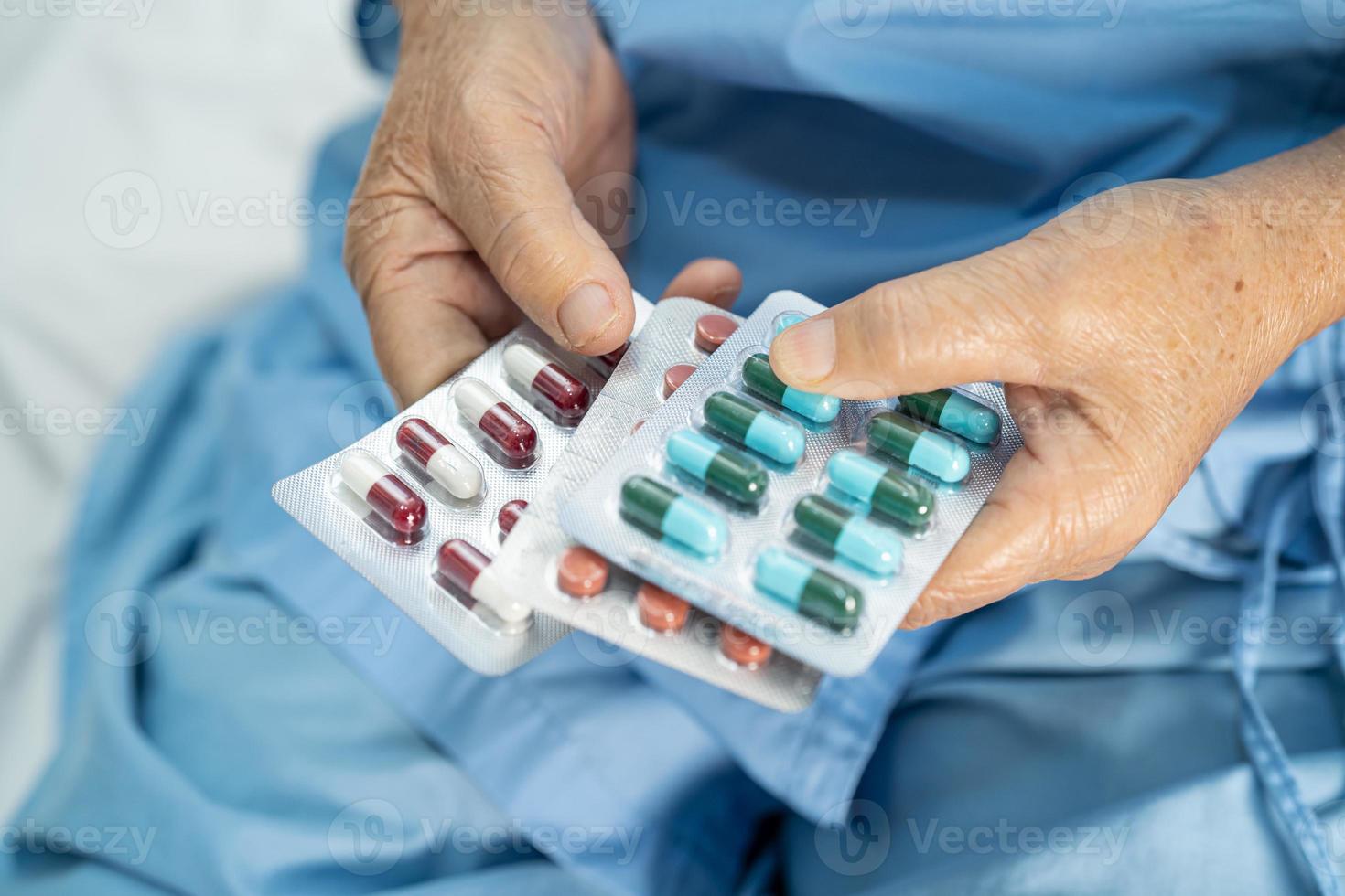 Asian senior elderly old lady woman holding Vitamin c pills drug in her hand, healthy strong medical concept. photo