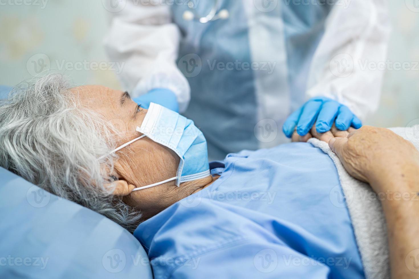 médico asiático con protector facial y traje de ppe nuevo normal para comprobar que el paciente protege la seguridad infección brote de coronavirus covid-19 en la sala de cuarentena del hospital de enfermería. foto