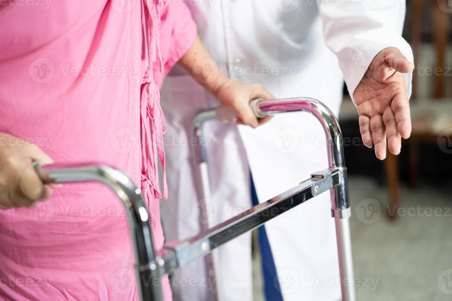 El médico ayuda y cuida a la anciana asiática mayor o anciana que usa un andador con una salud fuerte mientras camina en el hospital. foto