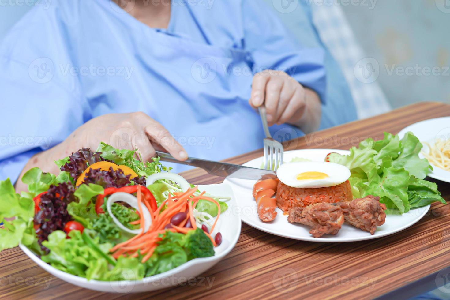 Paciente asiático mayor o anciano mujer desayunando vegetales alimentos saludables con esperanza y feliz mientras está sentado y hambriento en la cama en el hospital. foto