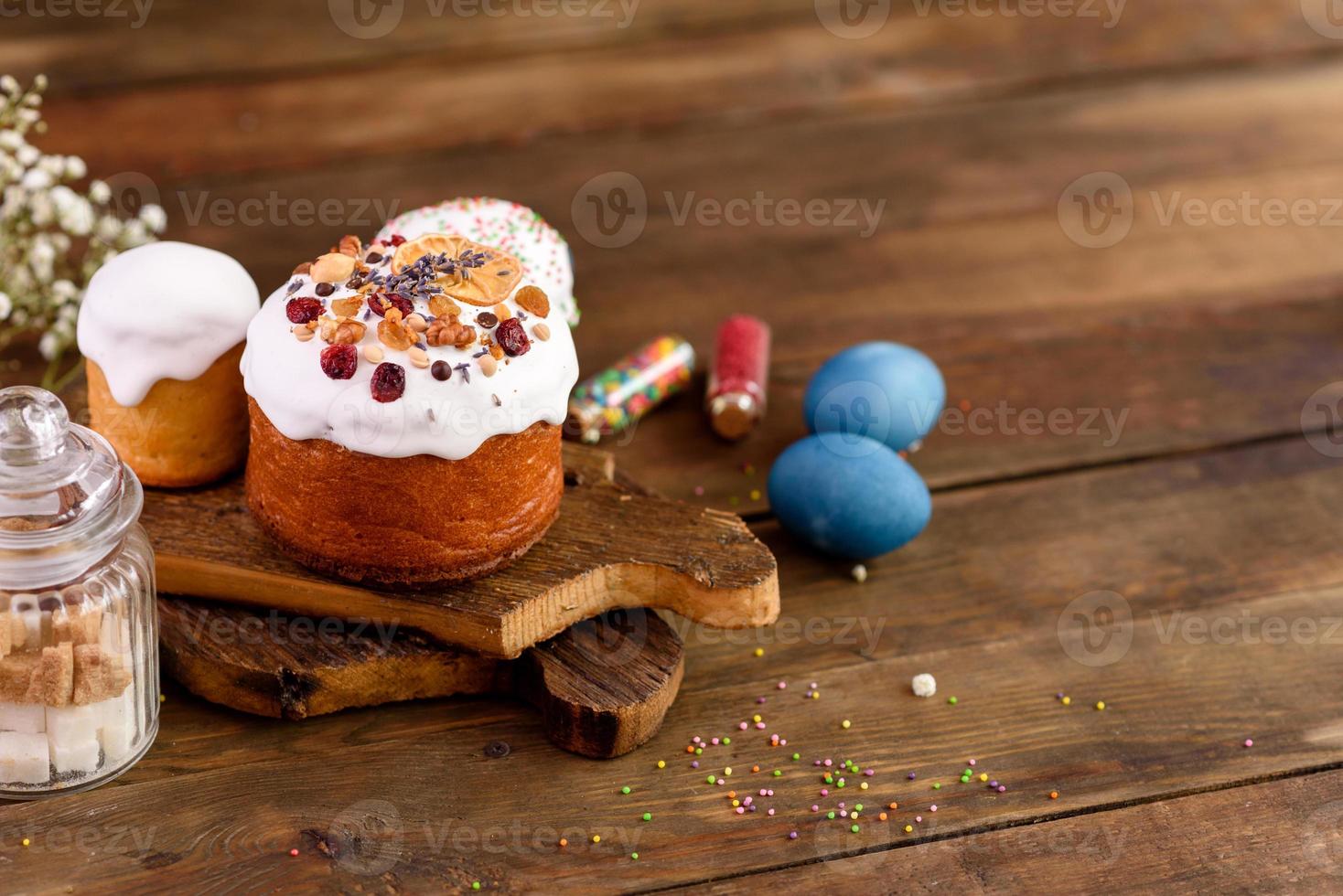 Pasteles festivos con glaseado blanco, nueces y pasas con huevos de pascua en la mesa festiva foto
