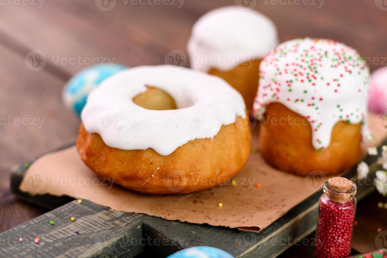 Pasteles festivos con glaseado blanco, nueces y pasas con huevos de pascua en la mesa festiva foto