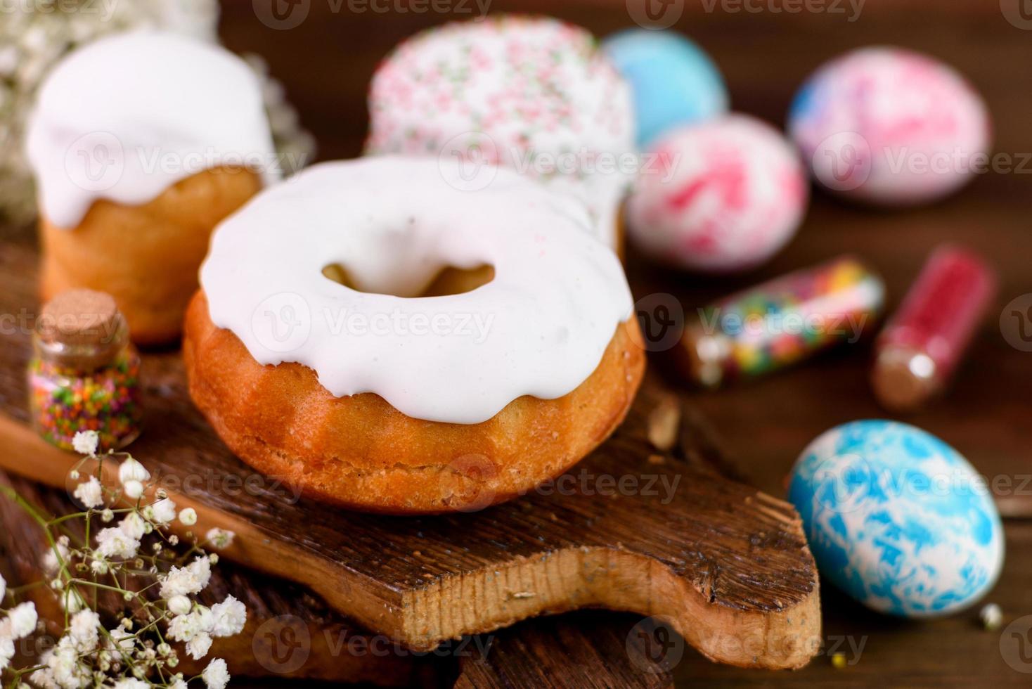 Pasteles festivos con glaseado blanco, nueces y pasas con huevos de pascua en la mesa festiva foto