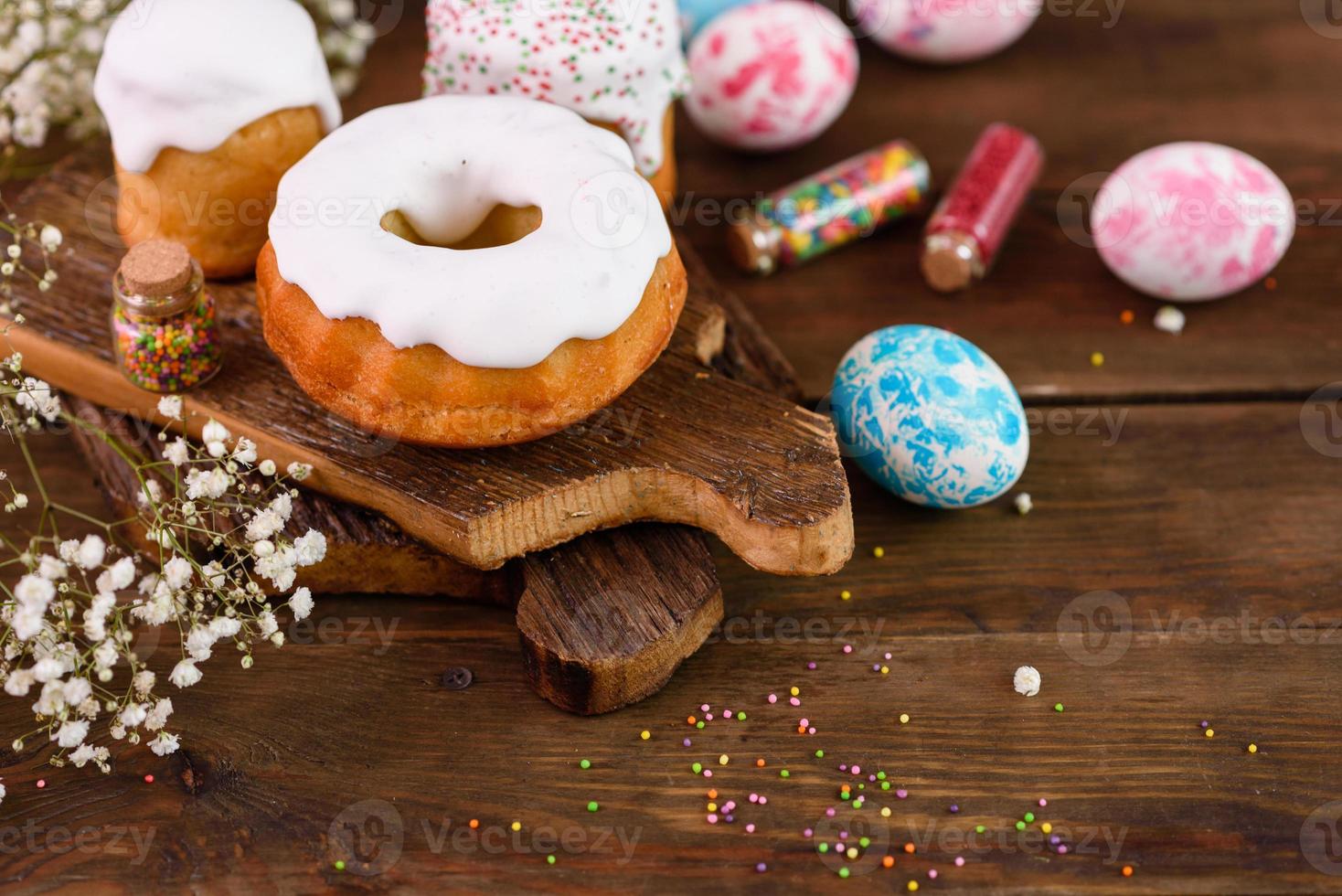 Pasteles festivos con glaseado blanco, nueces y pasas con huevos de pascua en la mesa festiva foto