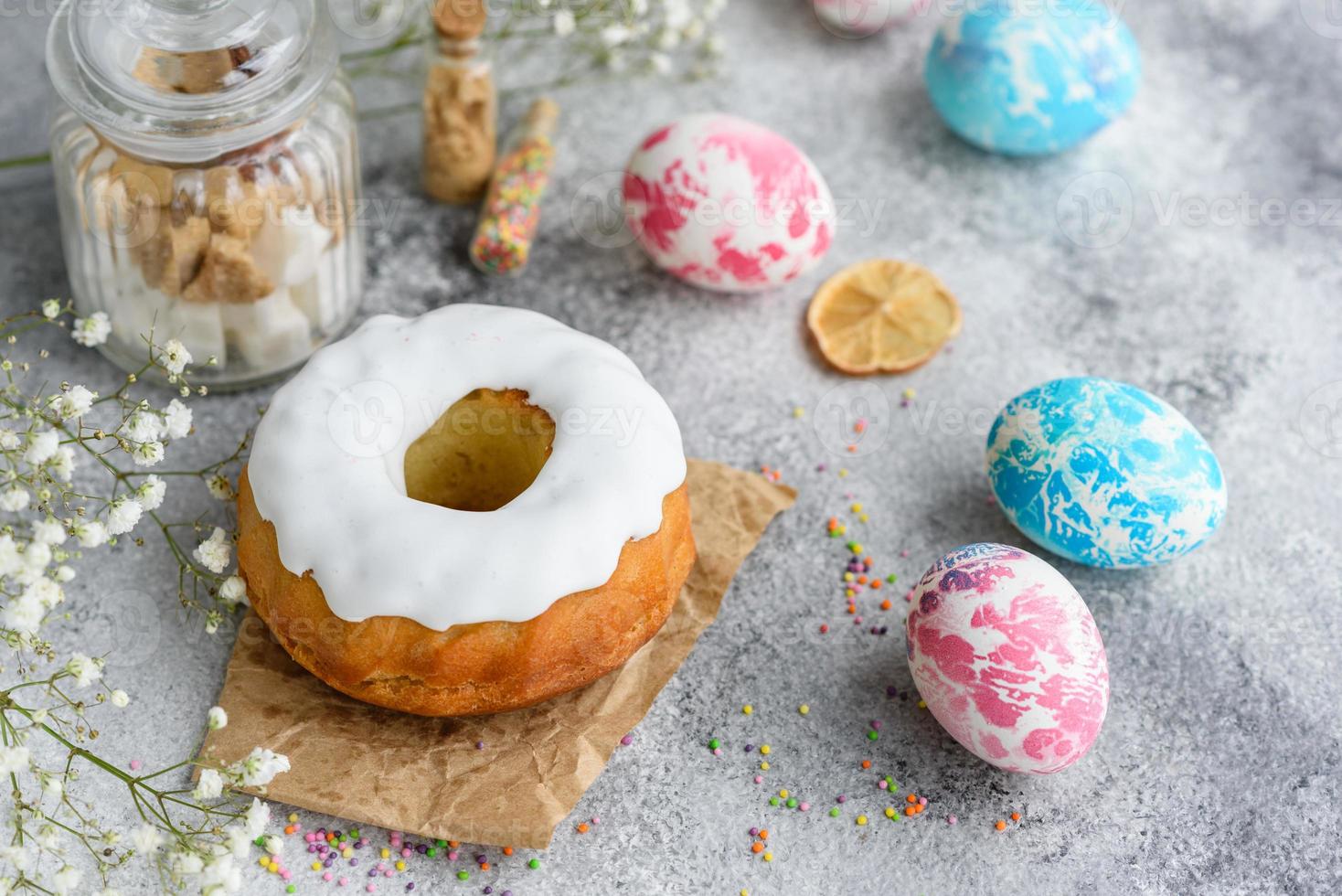 Pasteles festivos con glaseado blanco, nueces y pasas con huevos de pascua en la mesa festiva foto