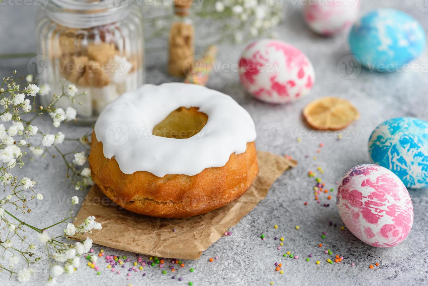 Festive cakes with white glaze, nuts and raisins with Easter eggs on the festive table photo