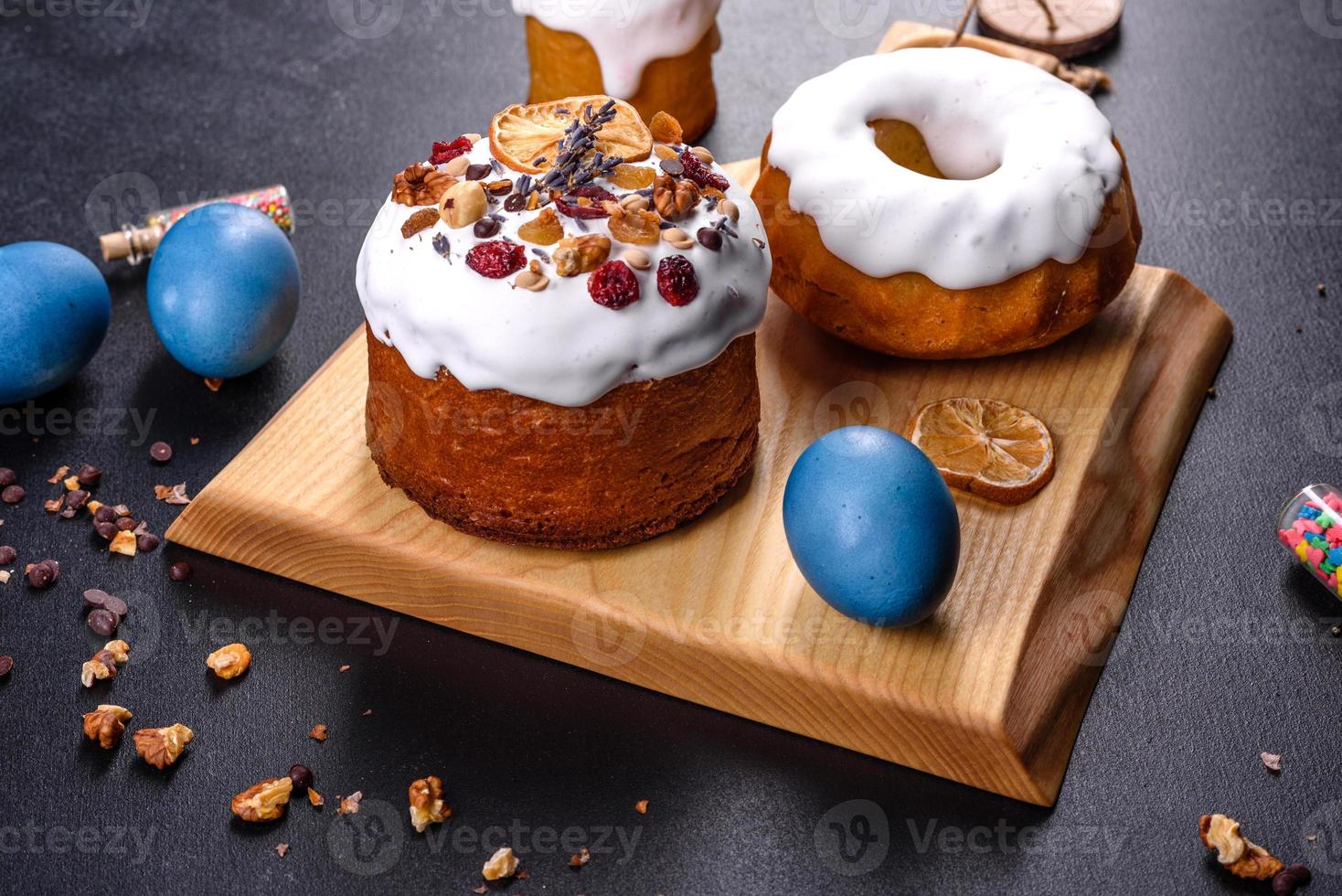 Pasteles festivos con glaseado blanco, nueces y pasas con huevos de pascua en la mesa festiva foto