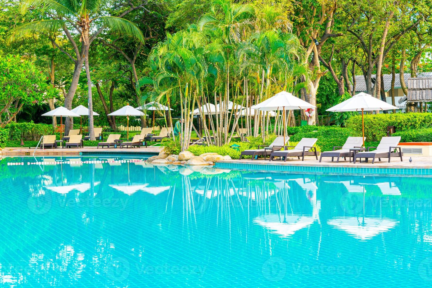 sombrilla y silla alrededor de la piscina en el hotel resort para viajes de placer y vacaciones cerca del mar océano playa foto