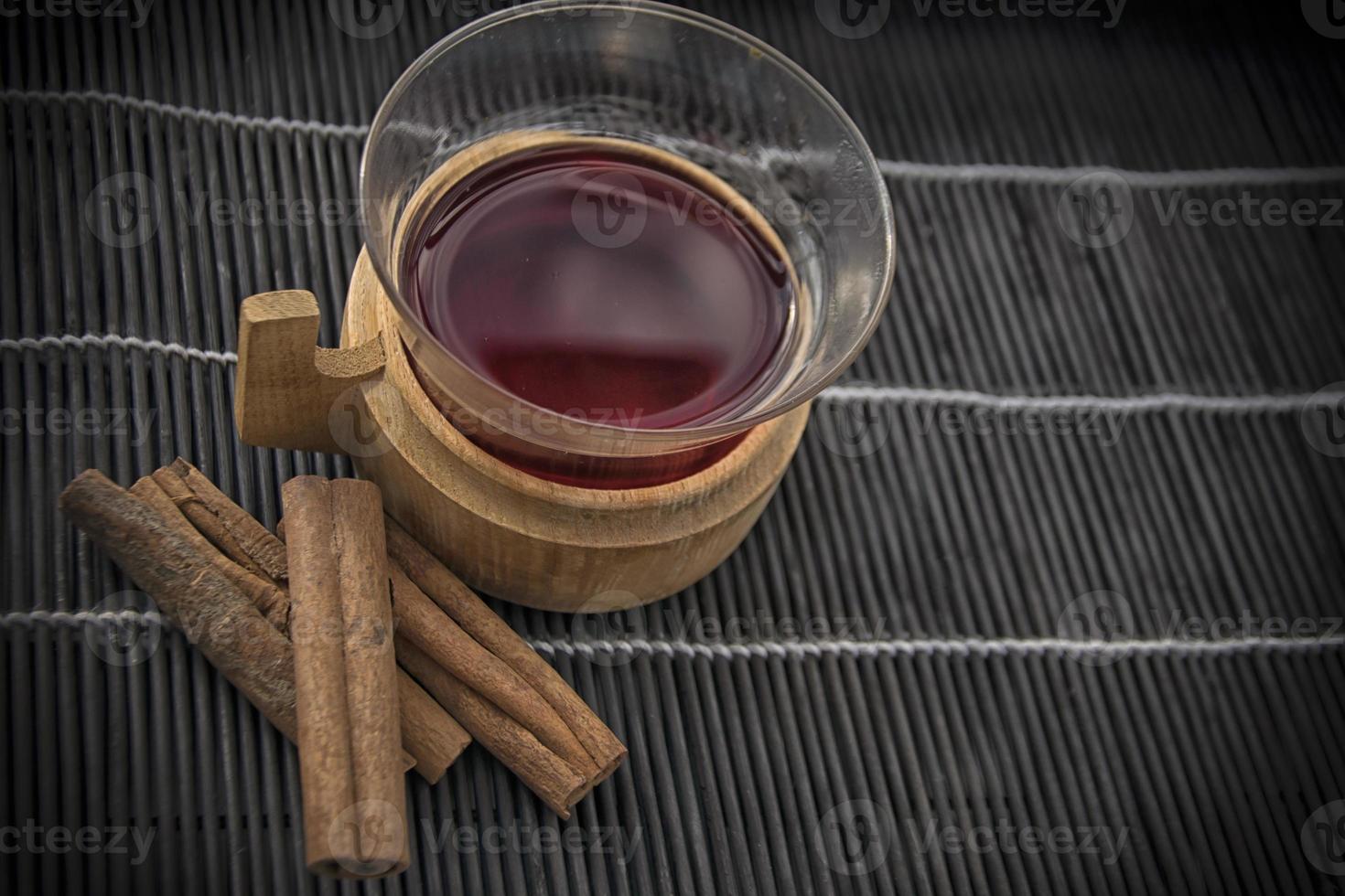 una taza de vino caliente sobre un fondo negro con canela en rama foto
