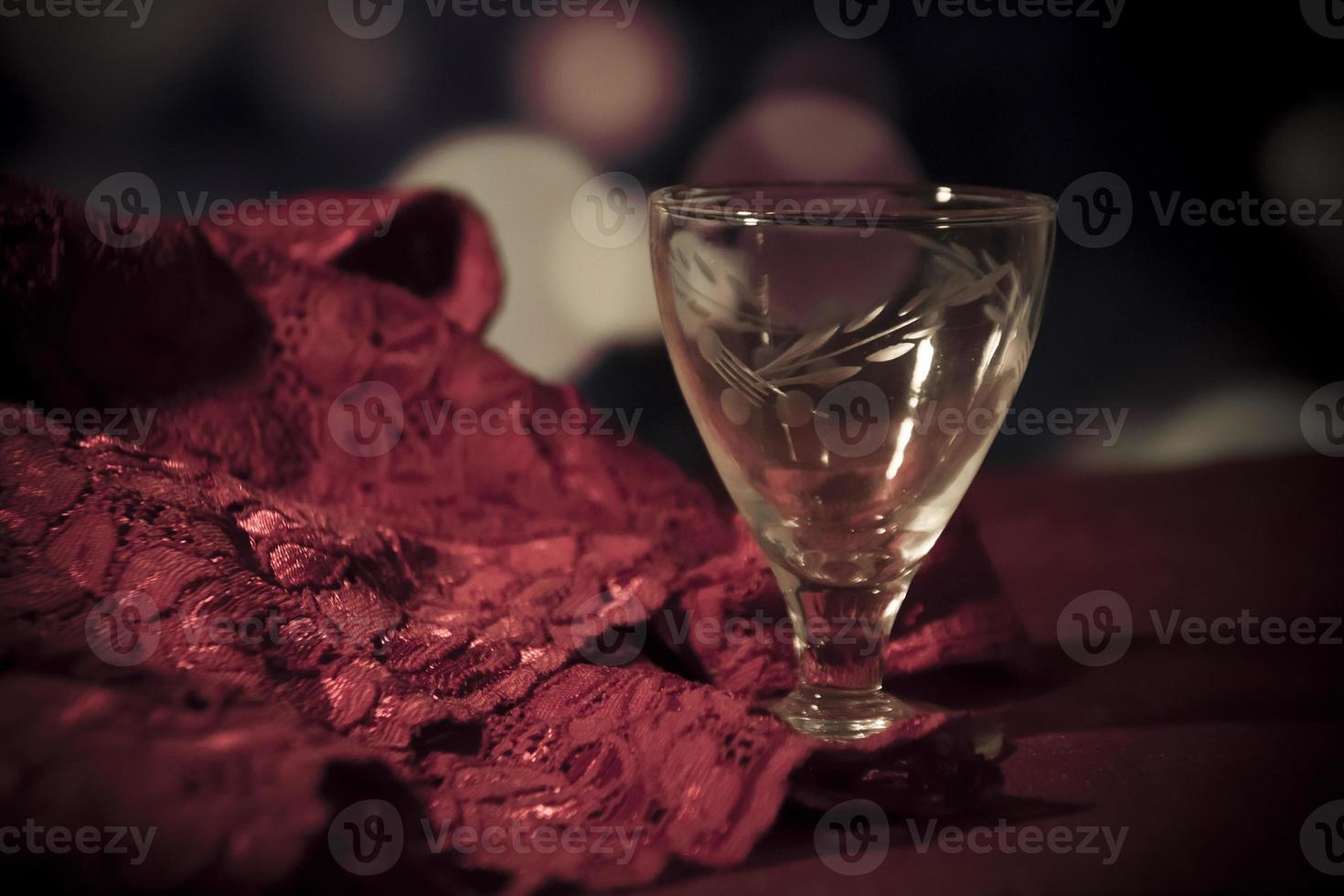 Sensual red lace and an empty brandy glass on a table photo