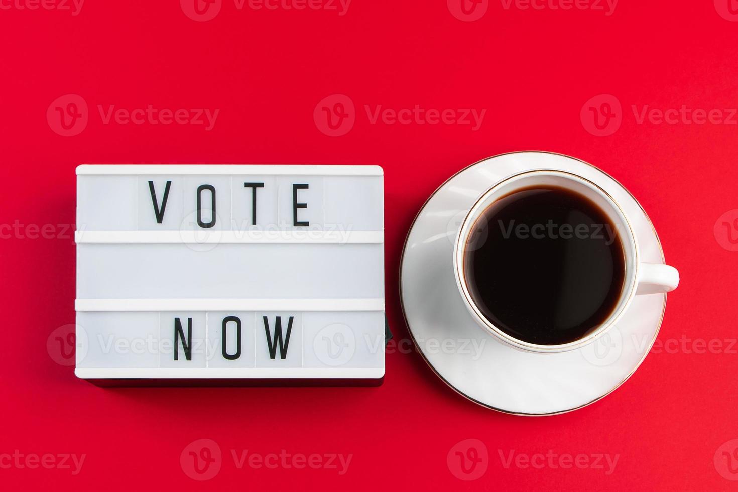 Vote now. Sign and cup of coffee on red background. Election voting concept. photo