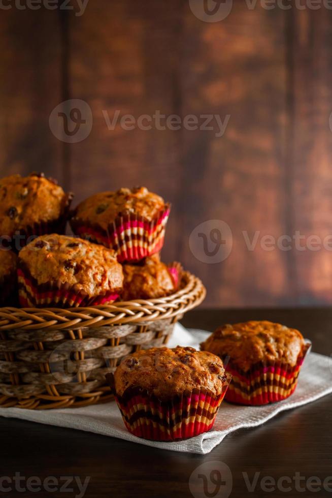 Muffins with raisins on a wooden background. Cupcake in a paper mold on a white napkin. photo