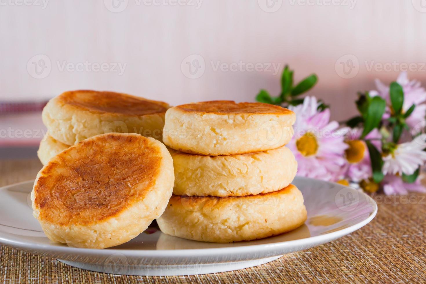 Cheesecakes on a plate on a brown background. Dish of cottage cheese for breakfast. photo