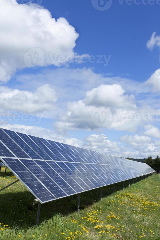 Estación de energía solar en la pradera de flores de primavera foto