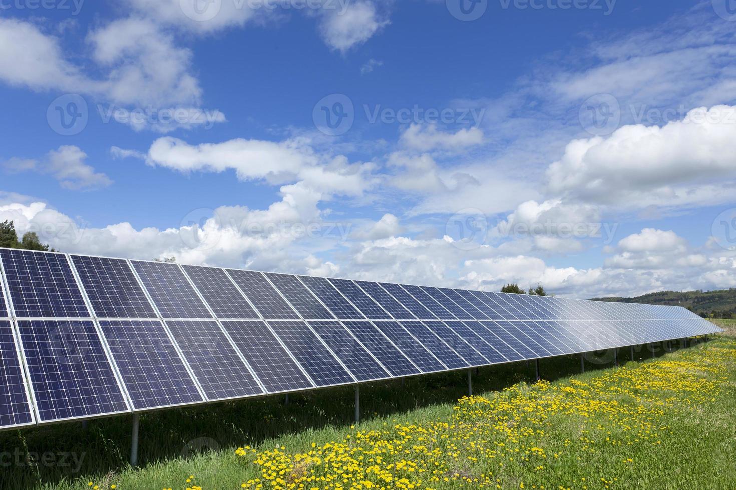 Estación de energía solar en la pradera de flores de primavera foto