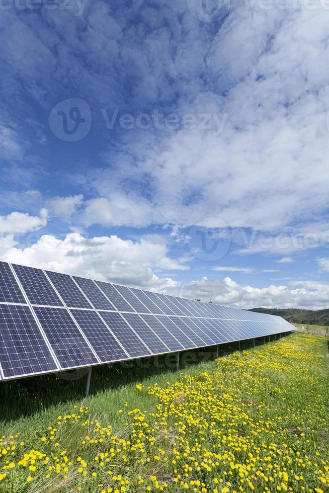 Estación de energía solar en la pradera de flores de primavera foto