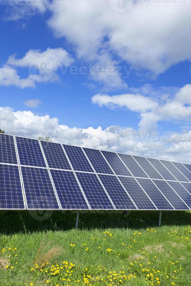 Estación de energía solar en la pradera de flores de primavera foto