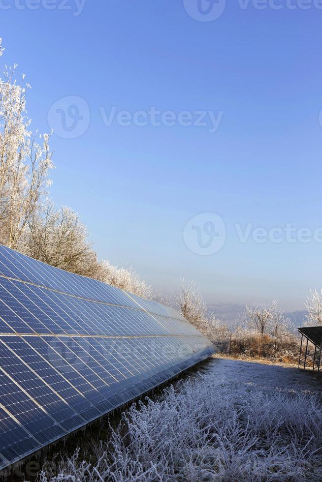 Estación de energía solar en la naturaleza nevada del invierno congelado foto