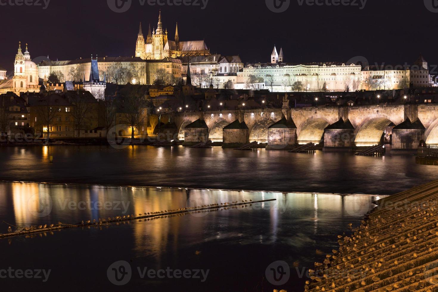 Night colorful snowy Christmas Prague Lesser Town with gothic Castle and Charles Bridge, Czech republic photo