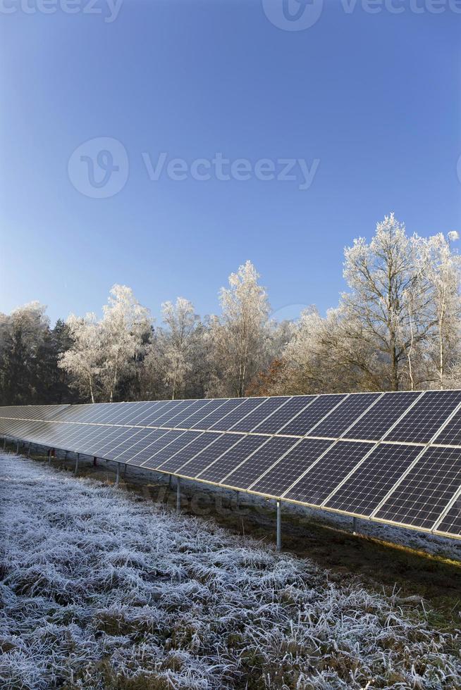 Estación de energía solar en la naturaleza nevada del invierno congelado foto