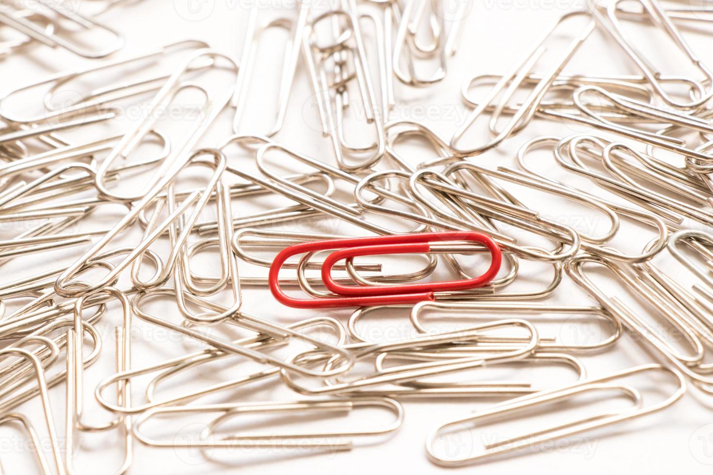 Red paper clip show different from the others on white background photo