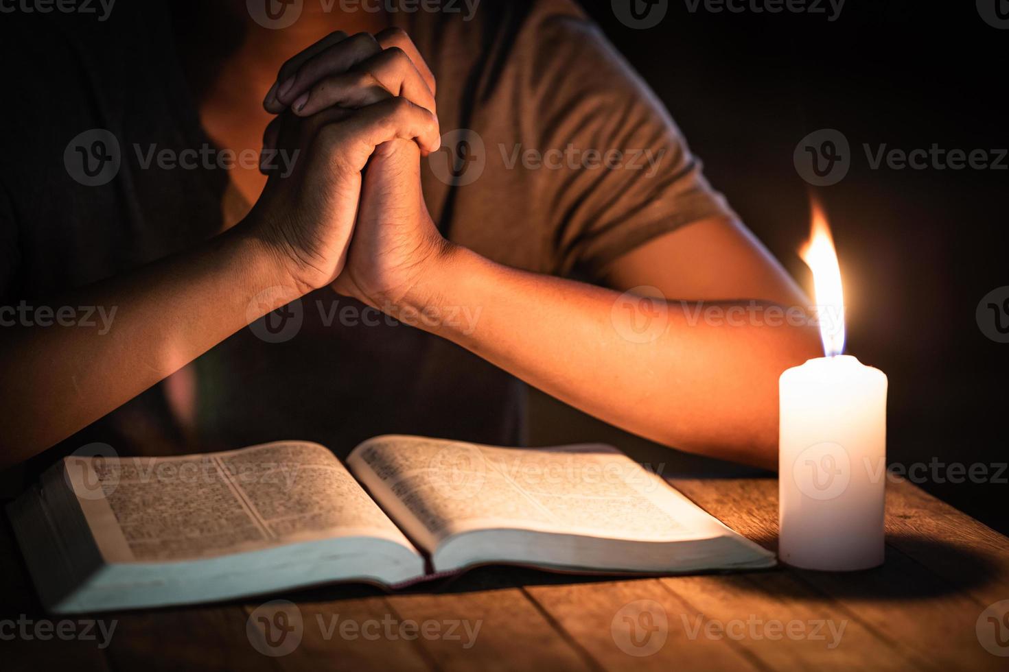 Conceptos religiosos, el joven oró sobre la Biblia en la habitación y encendió las velas para iluminar. foto