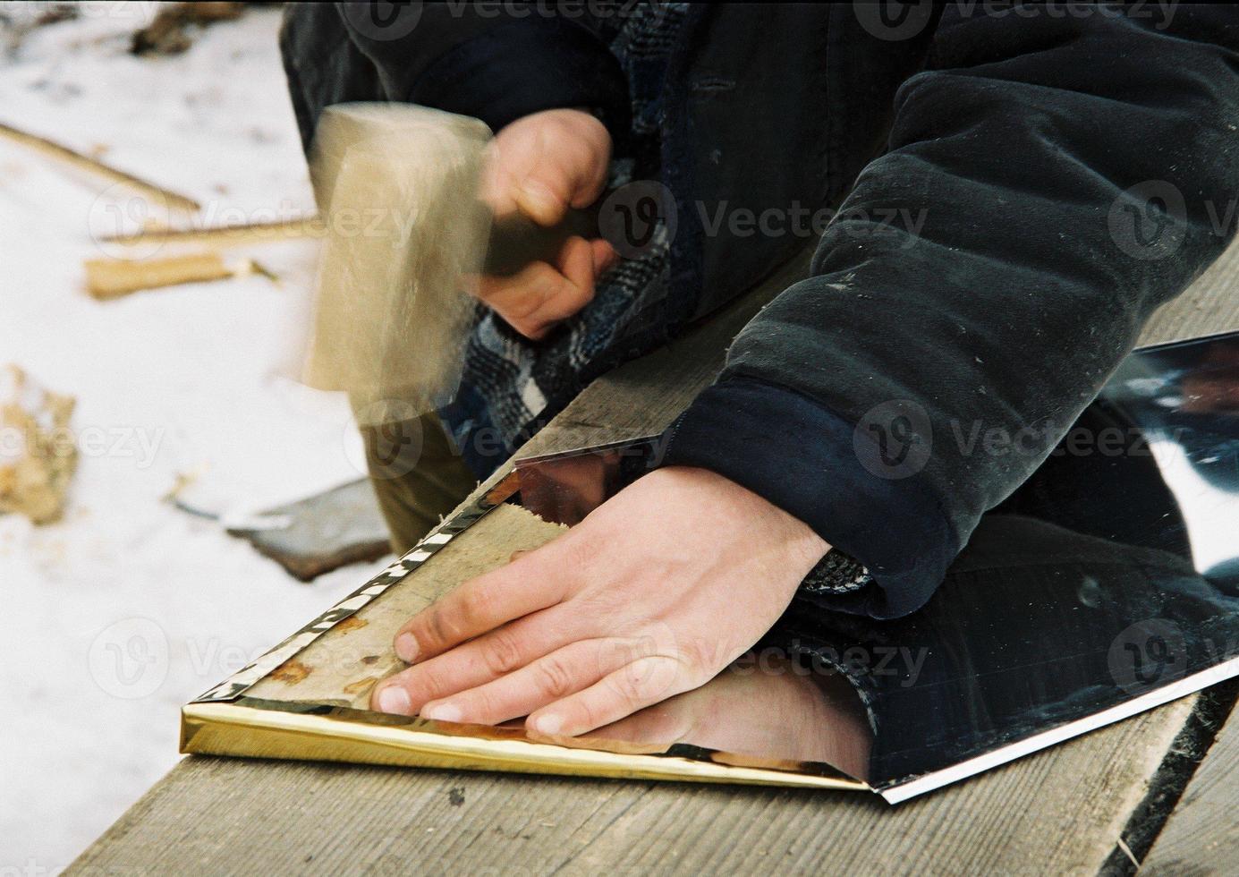 The photo depicts a man with a hammer knocks the yellow metal