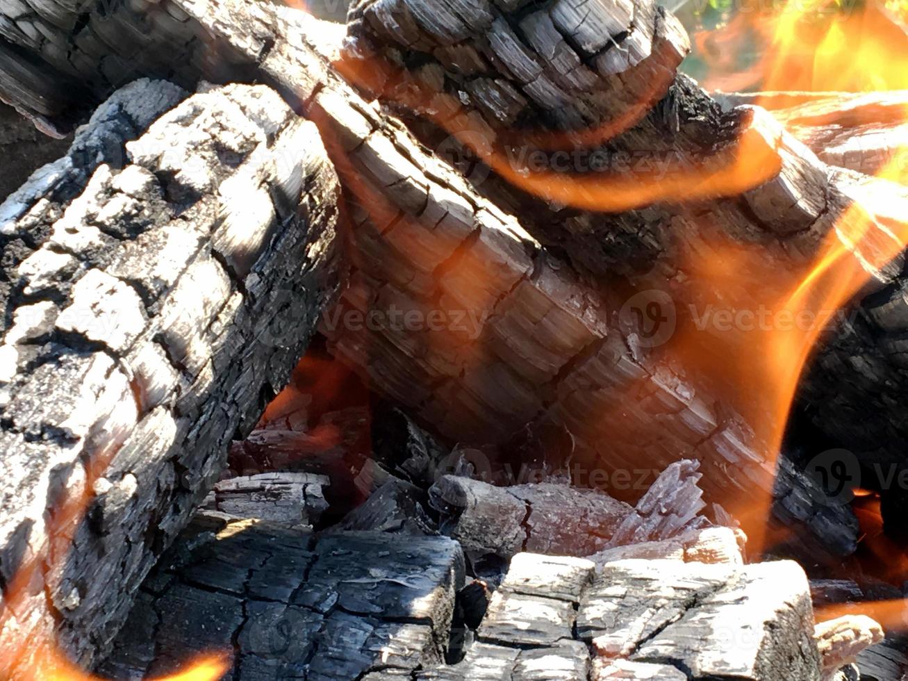 Beautiful red flame from slice wood, dark grey black coals inside metal brazier photo