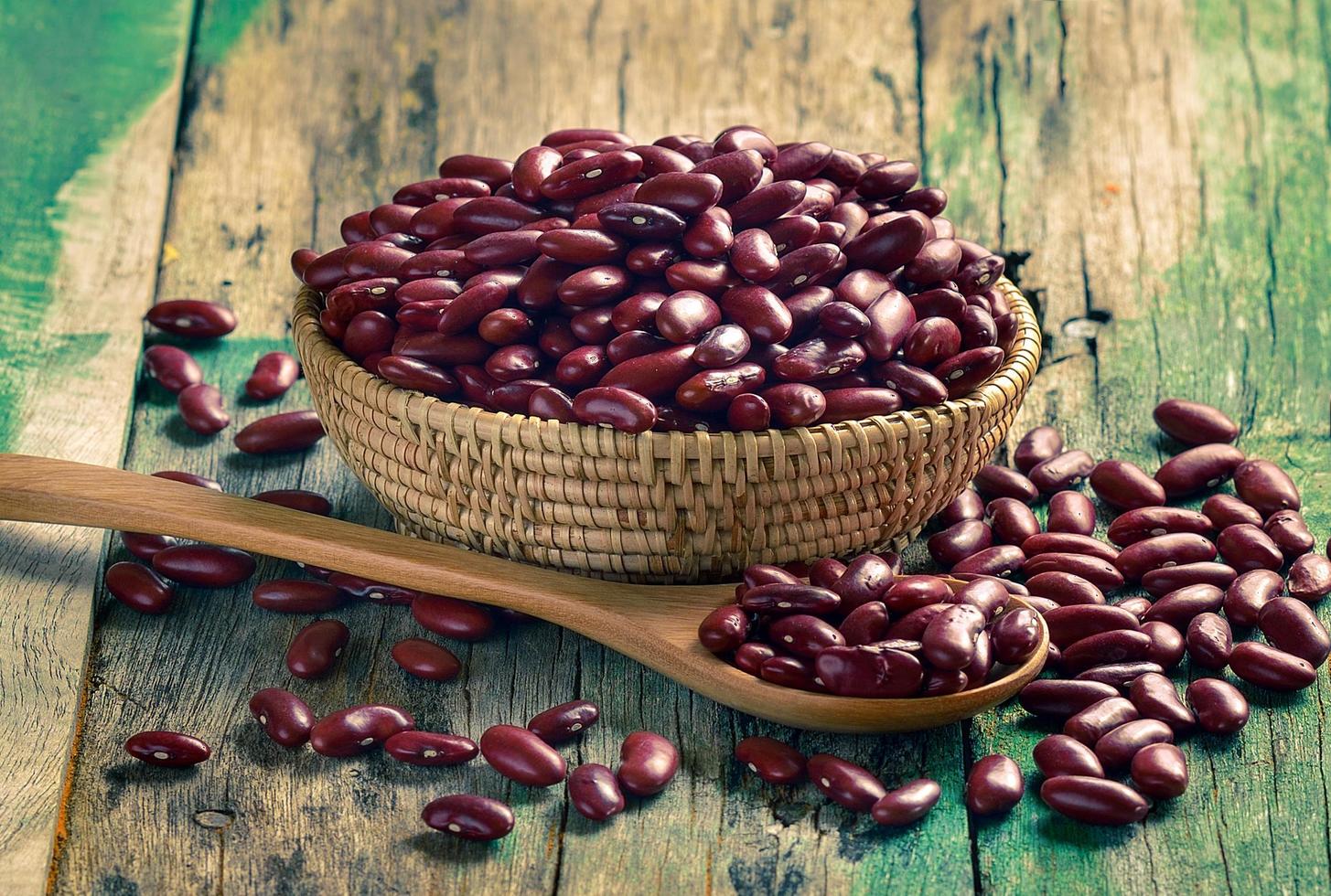 Frijoles rojos en el cuenco de madera sobre madera vieja foto