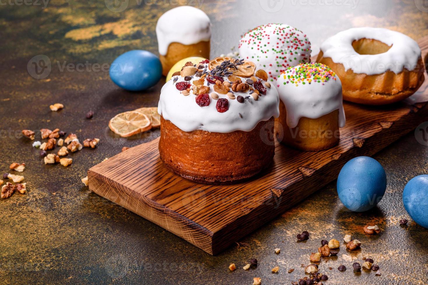 Festive cakes with white glaze, nuts and raisins with Easter eggs on the festive table photo