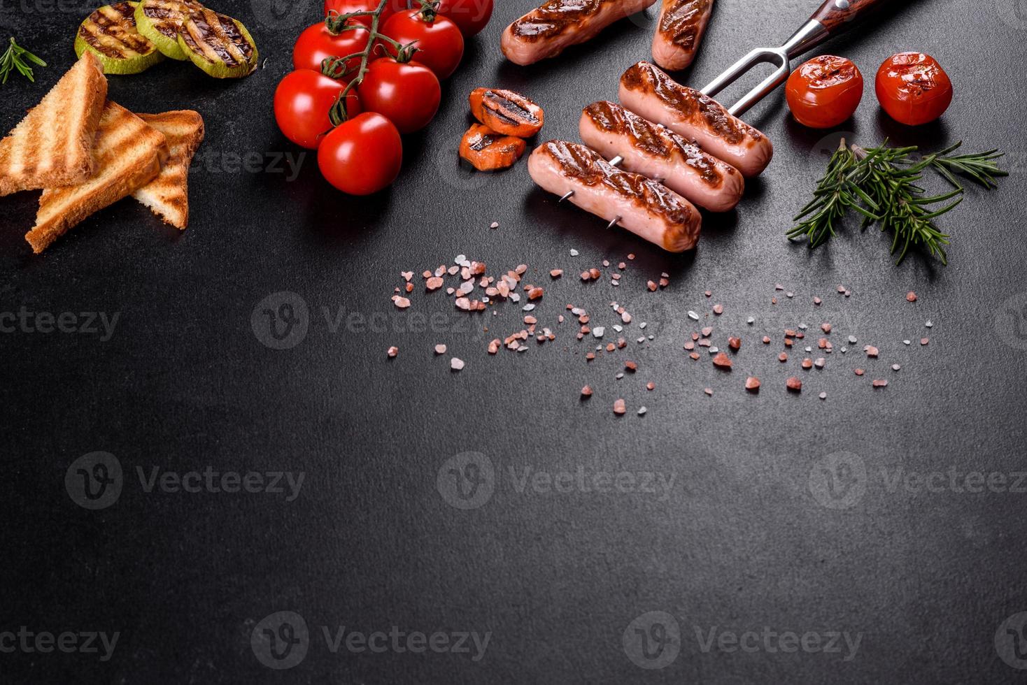 Salchichas frescas y sabrosas a la parrilla con verduras, especias y hierbas. foto