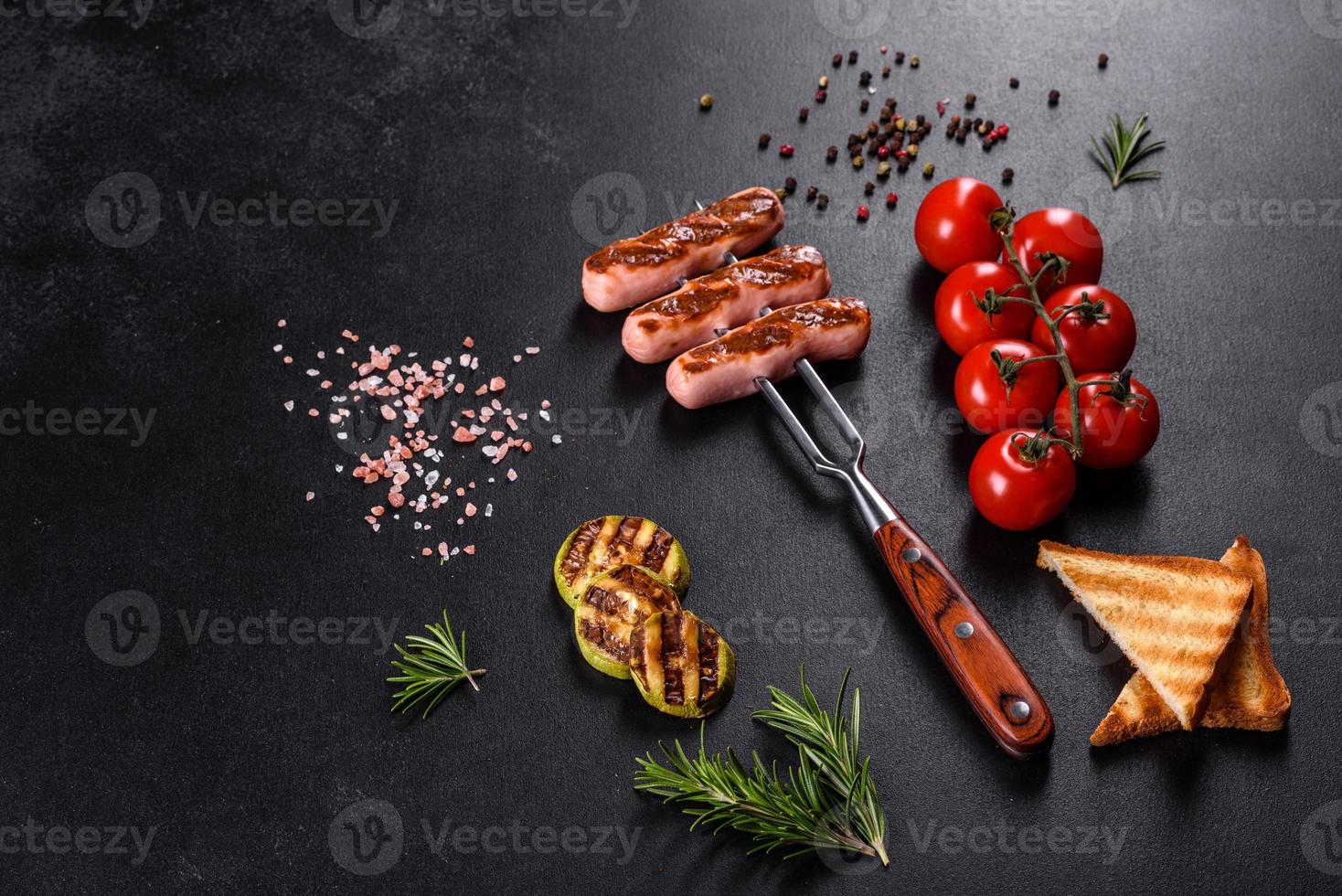 Salchichas frescas y sabrosas a la parrilla con verduras, especias y hierbas. foto