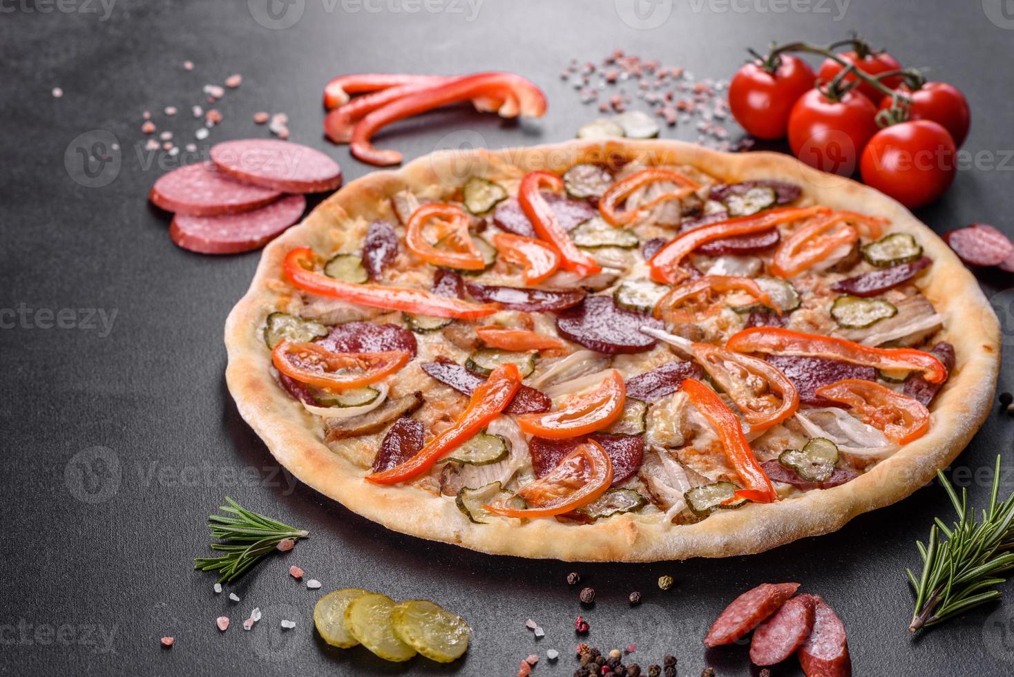 deliciosa pizza fresca hecha en un horno de solera con salchicha, pimiento y tomates foto