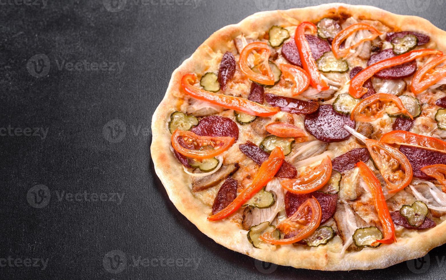 deliciosa pizza fresca hecha en un horno de solera con salchicha, pimiento y tomates foto