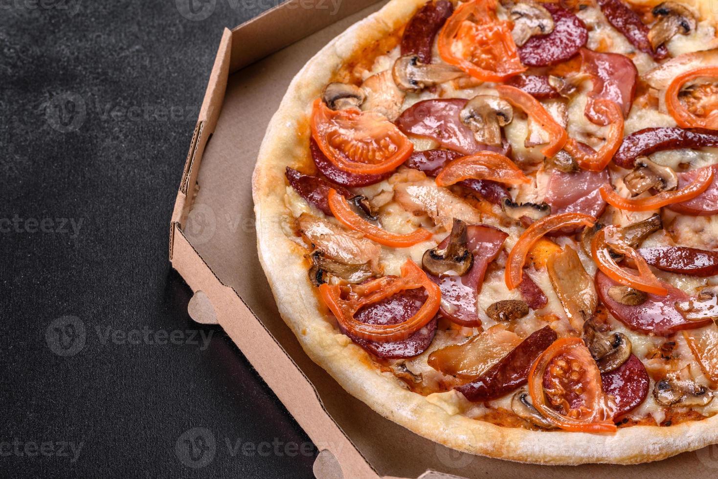 deliciosa pizza fresca hecha en un horno de solera con salchicha, pimiento y tomates foto