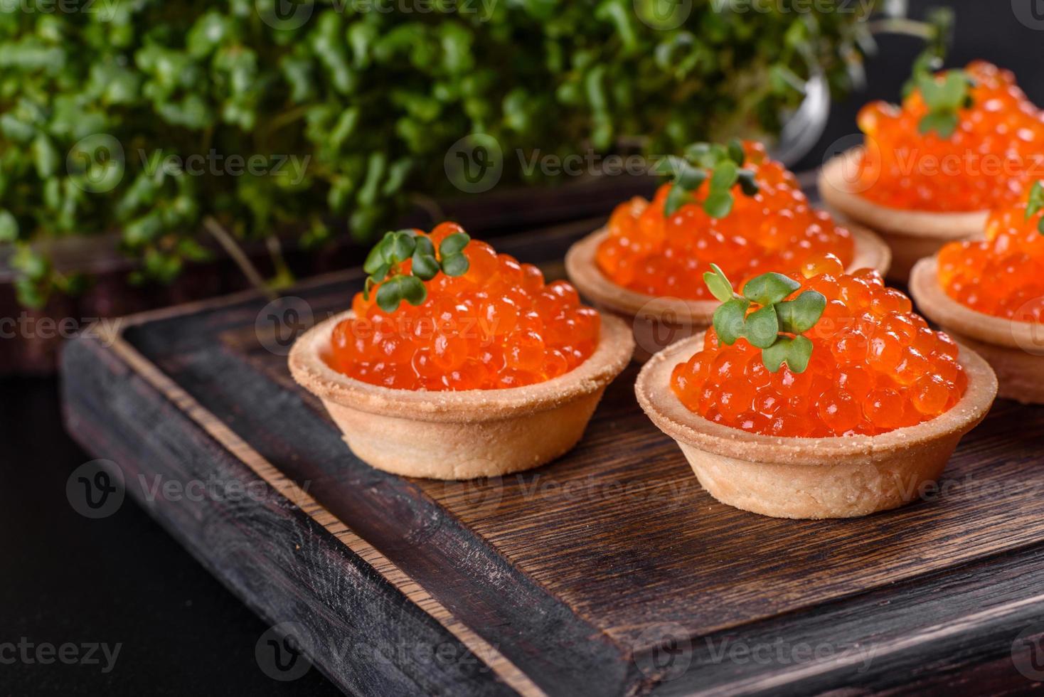 Delicioso caviar rojo fresco sobre una mesa de hormigón oscuro foto