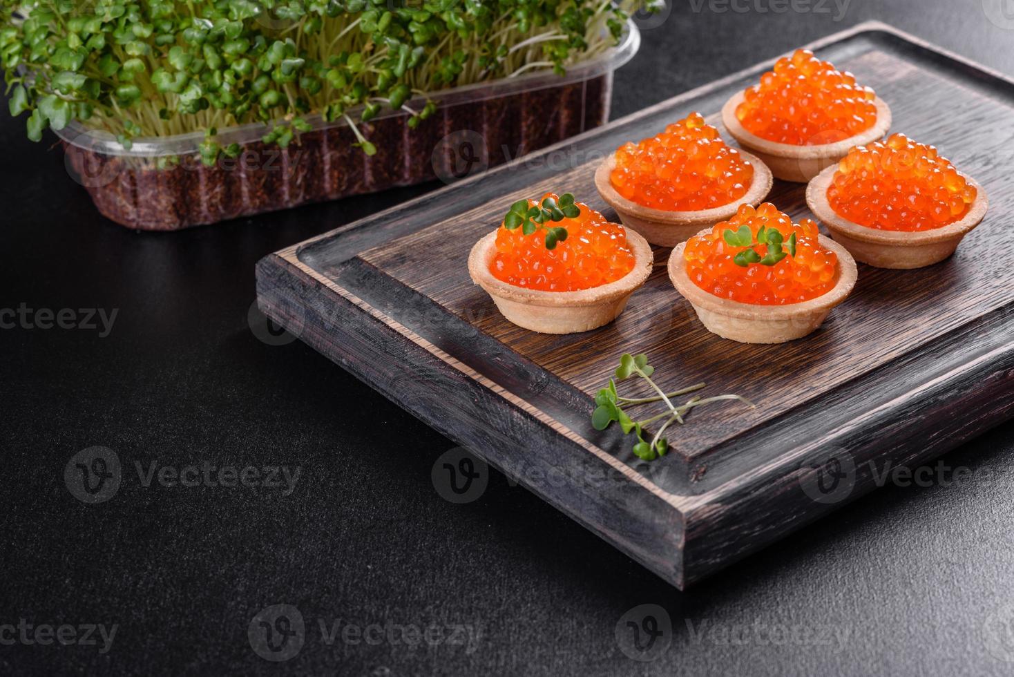 Delicioso caviar rojo fresco sobre una mesa de hormigón oscuro foto