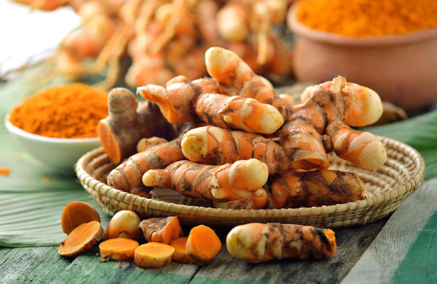 Fresh turmeric roots in the basket on wooden table photo