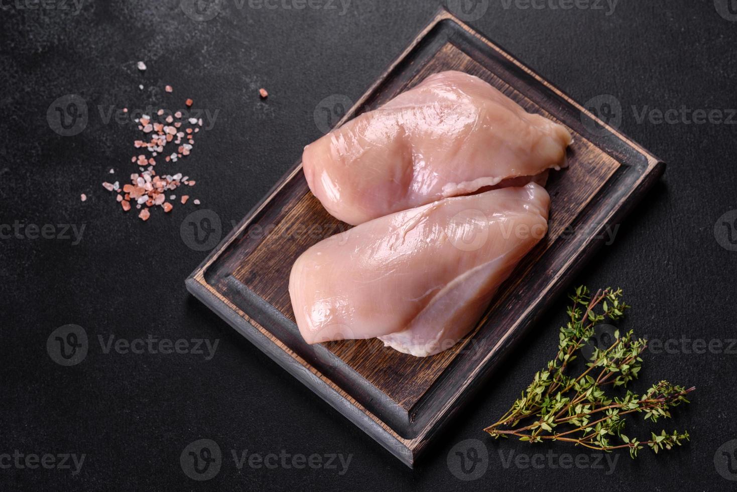 Fresh chicken fillet on a dark concrete table with spices and herbs photo