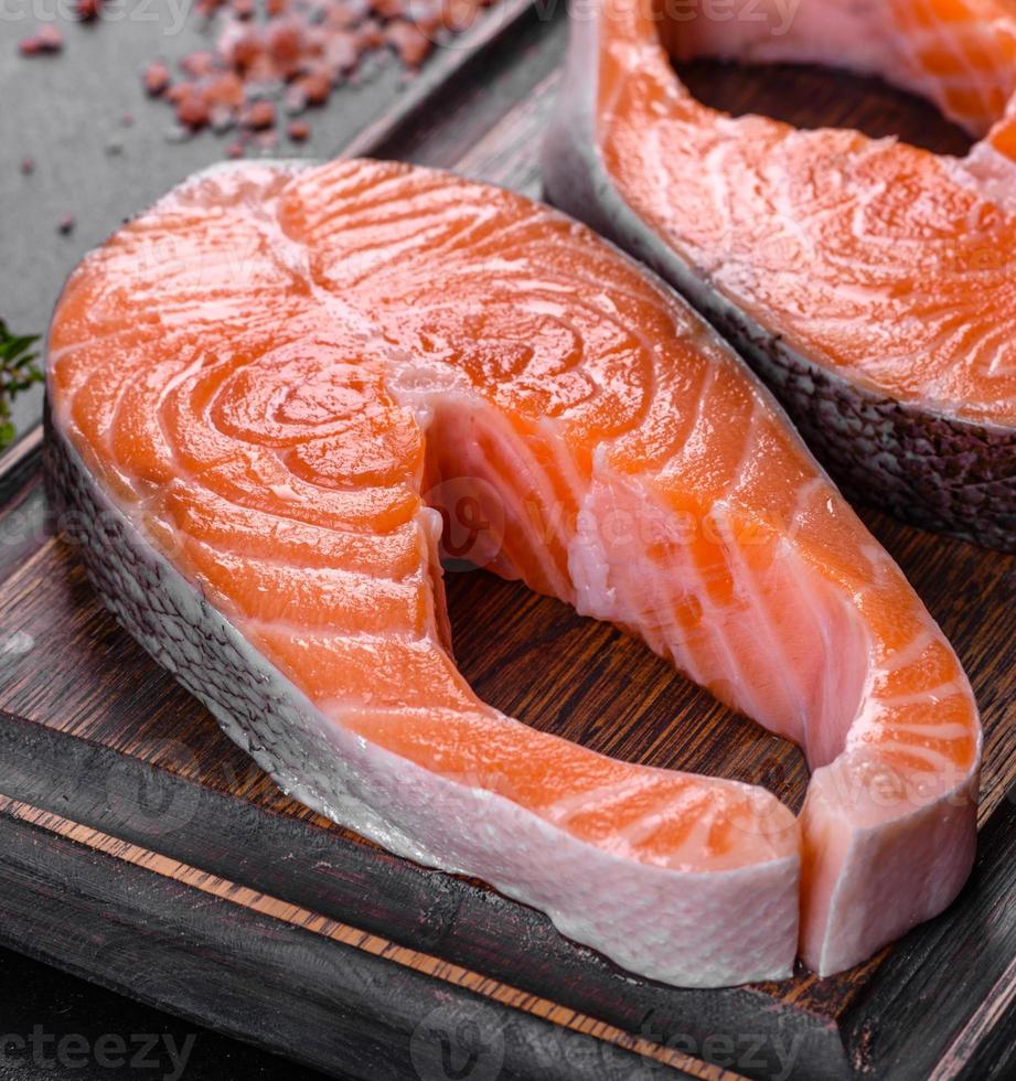 Fresh raw salmon steak with spices and herbs prepared for grilled baking photo