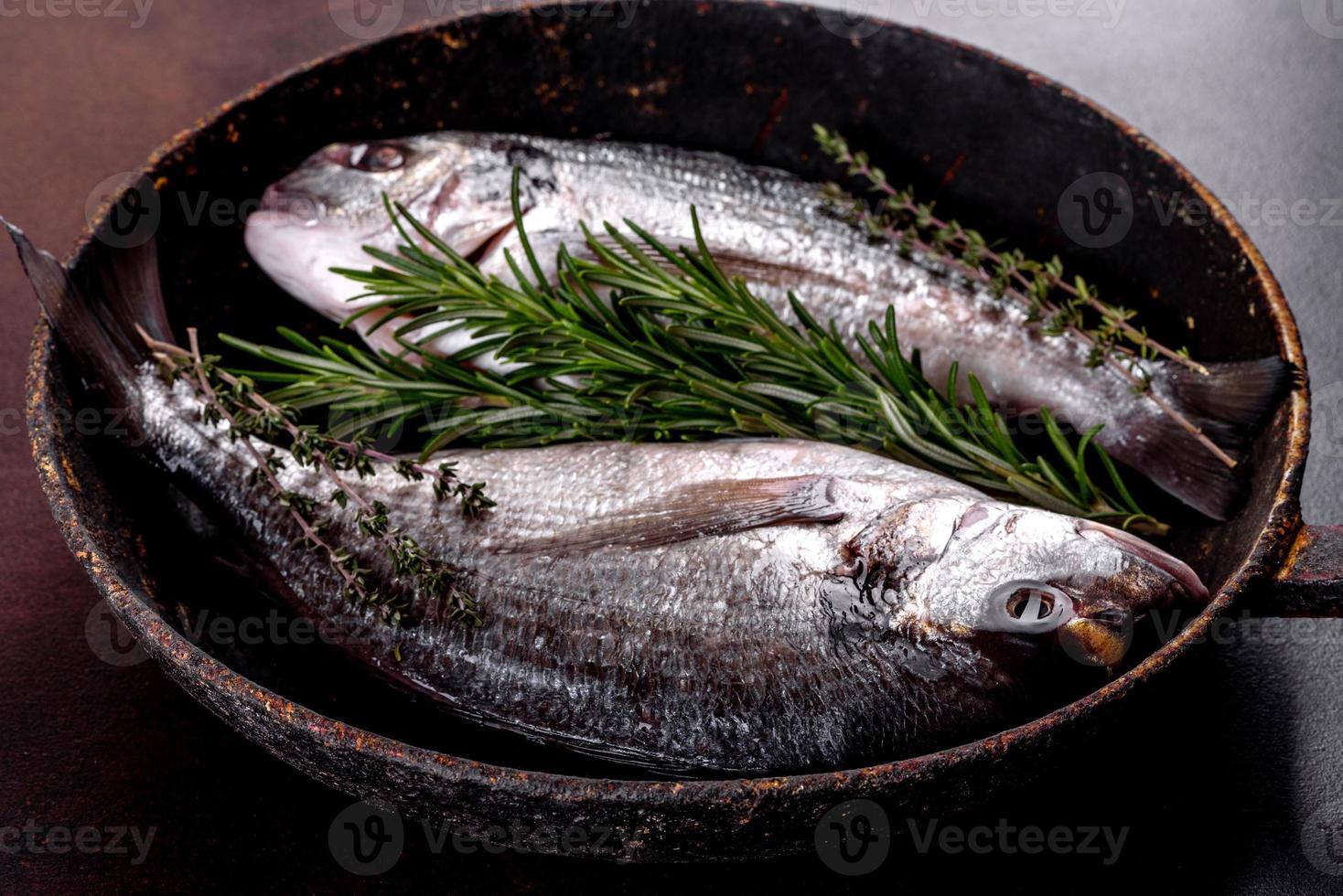 Raw dorado with spices and herbs in a pan is prepared for baking photo