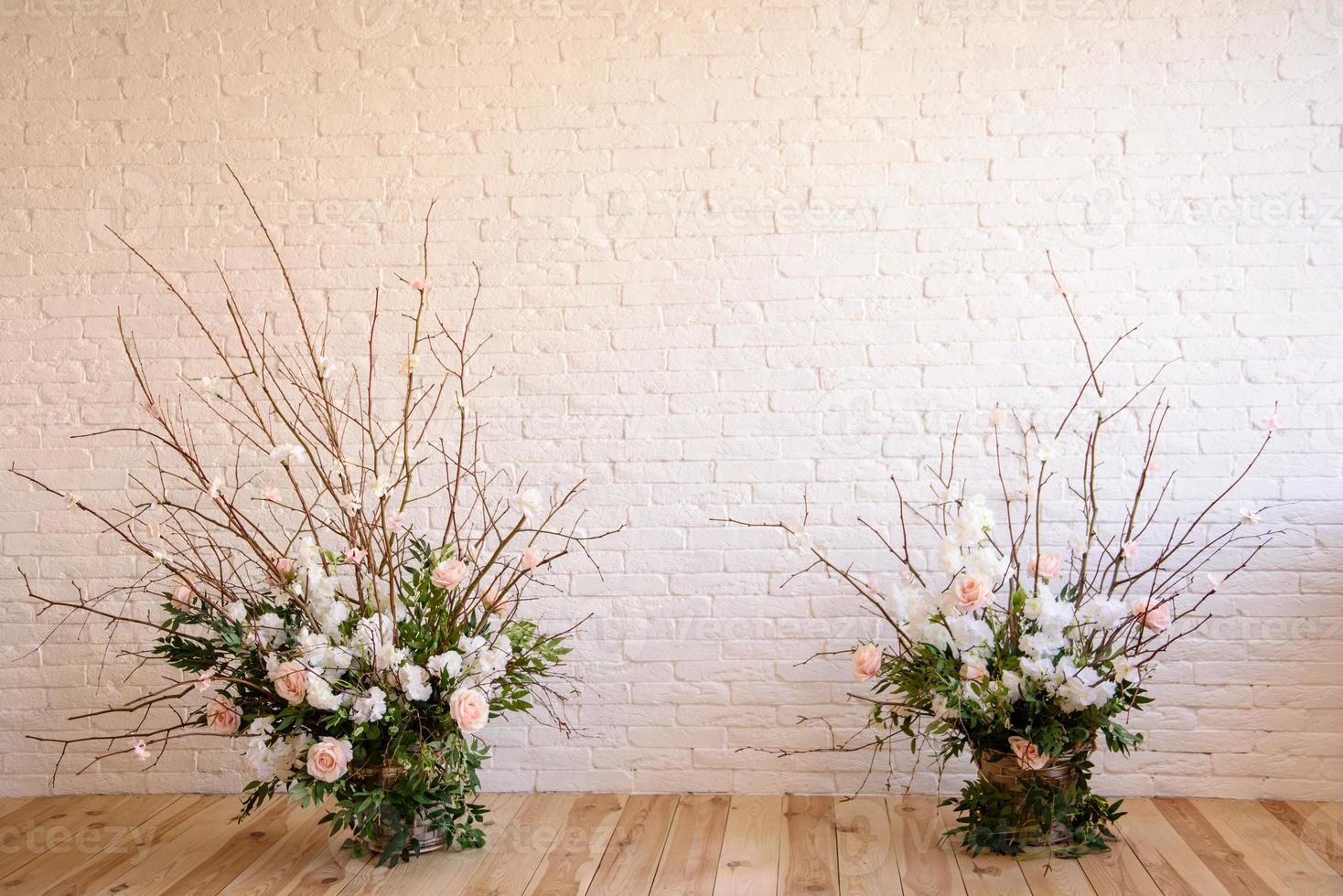 Decorations of branches with beautiful pink and white flowers in the basket against the background of a white brick wall photo