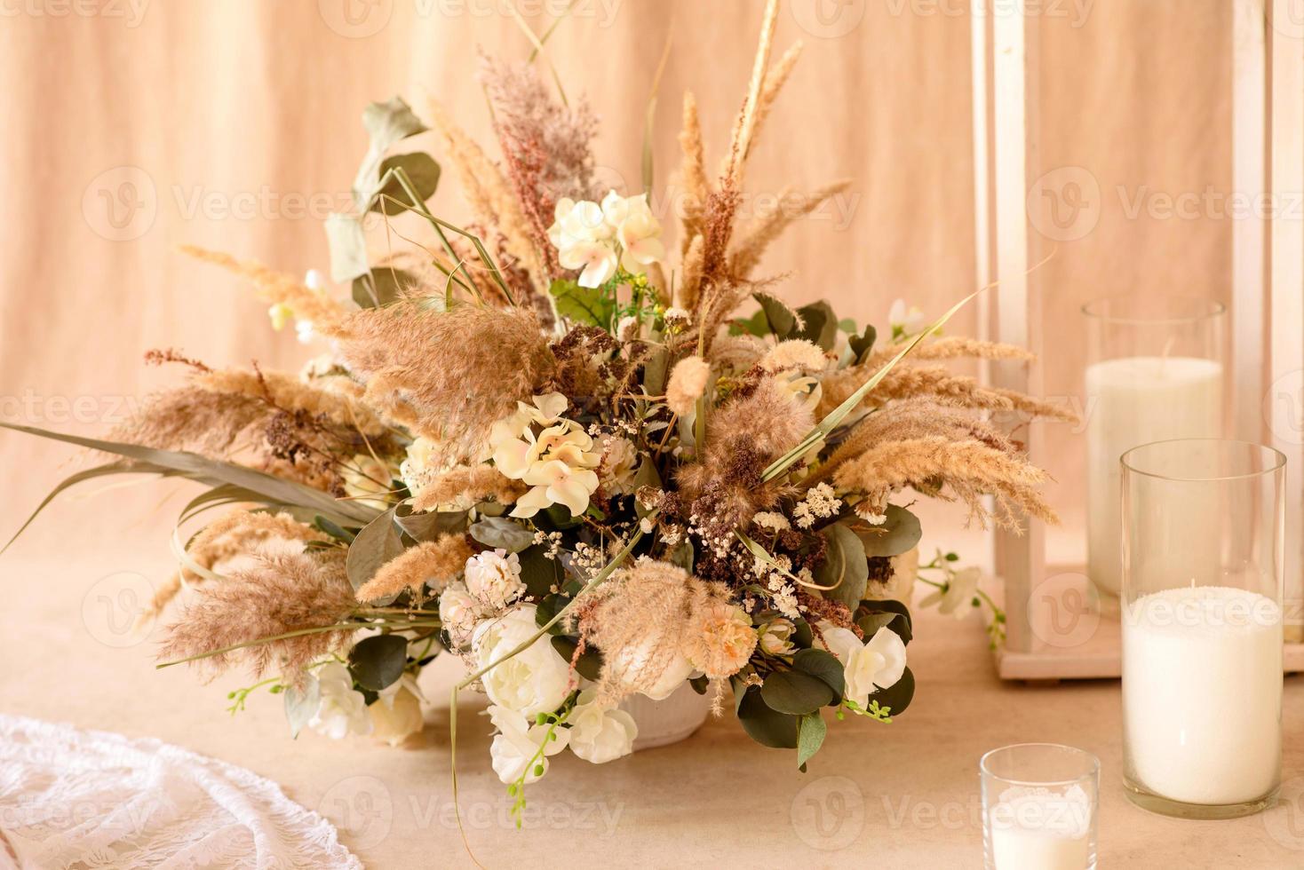 Decoraciones de hermosas flores secas en un jarrón blanco sobre un fondo de tela beige foto