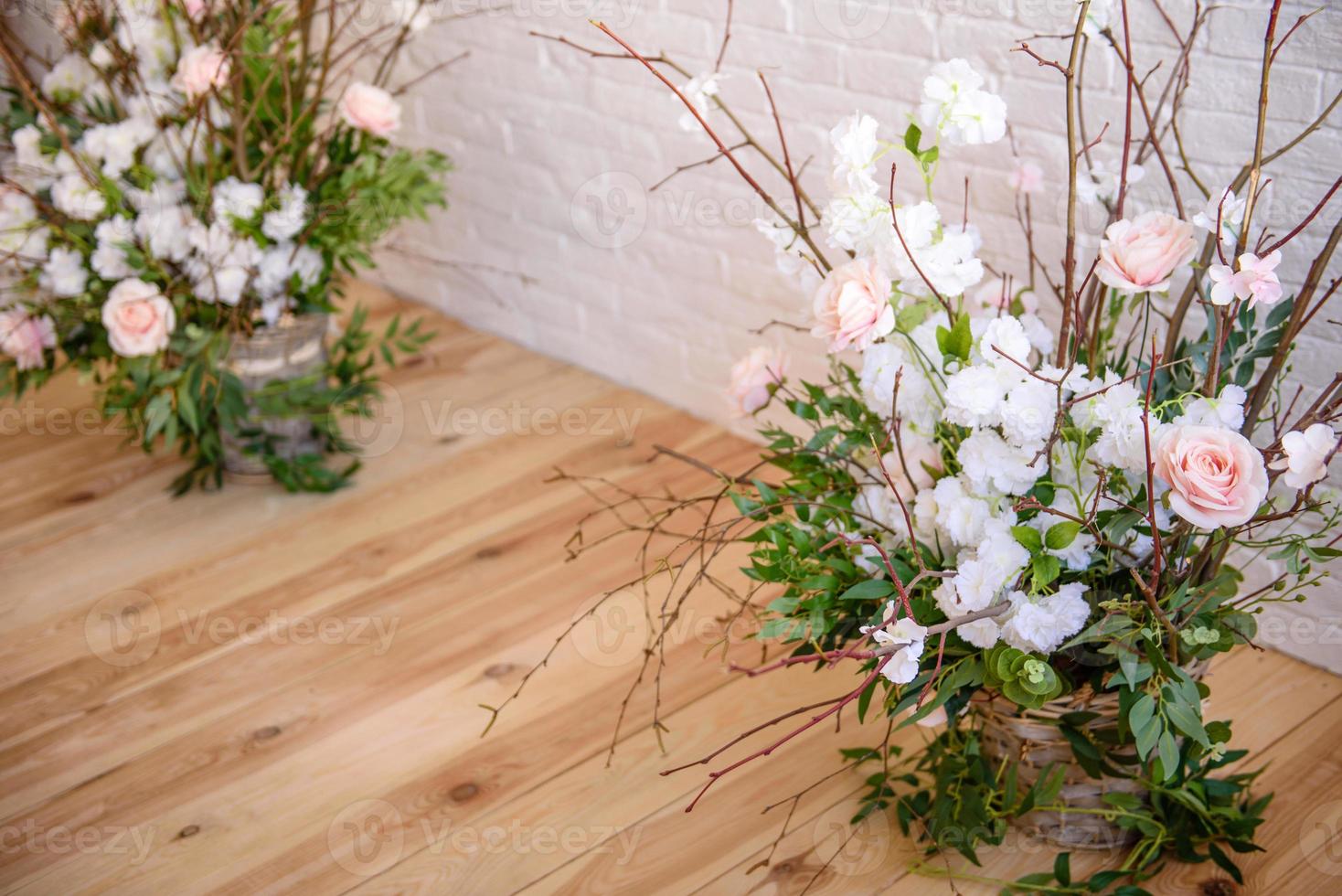 Decoraciones de ramas con hermosas flores rosas y blancas en la canasta con el telón de fondo de una pared de ladrillo blanco. foto